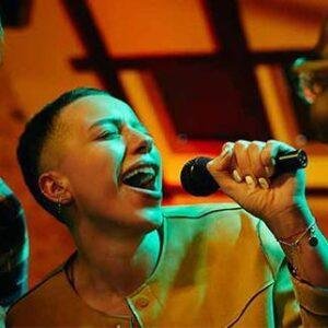 Person singing karaoke with a microphone under club lights.