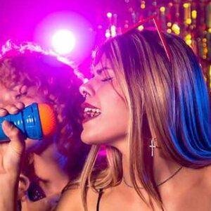 Two people singing karaoke with colourful stage lights and joyful expressions.