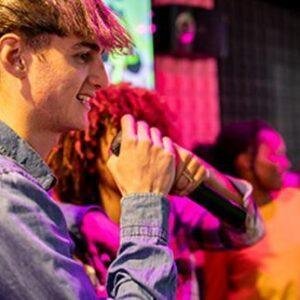 Man singing karaoke into a mic at a lively party.