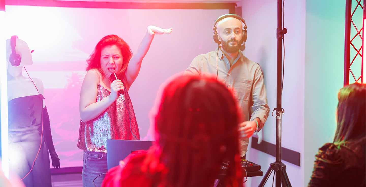 Man singing karaoke with crowd behind him on stage.