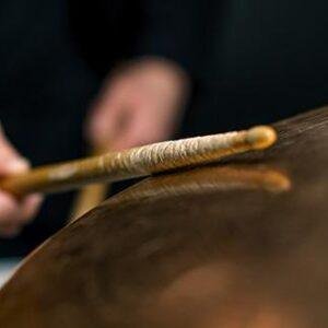 Drummer striking a cymbal with drumsticks during a performance
