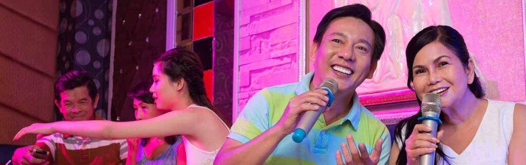 Couple singing karaoke on stage with vibrant pink lighting