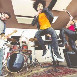 Band rehearsing in a studio while one member jumps energetically