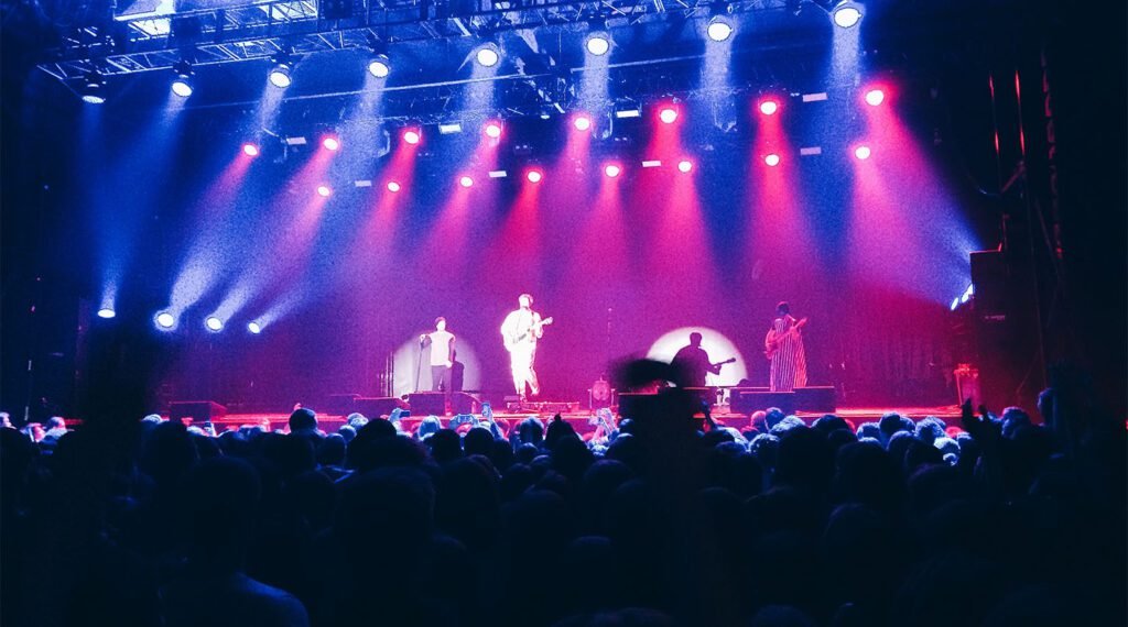 Large concert stage with performers and colourful lighting effects
