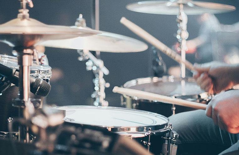 Close-up of a drum kit with cymbals and snare drum under stage lighting