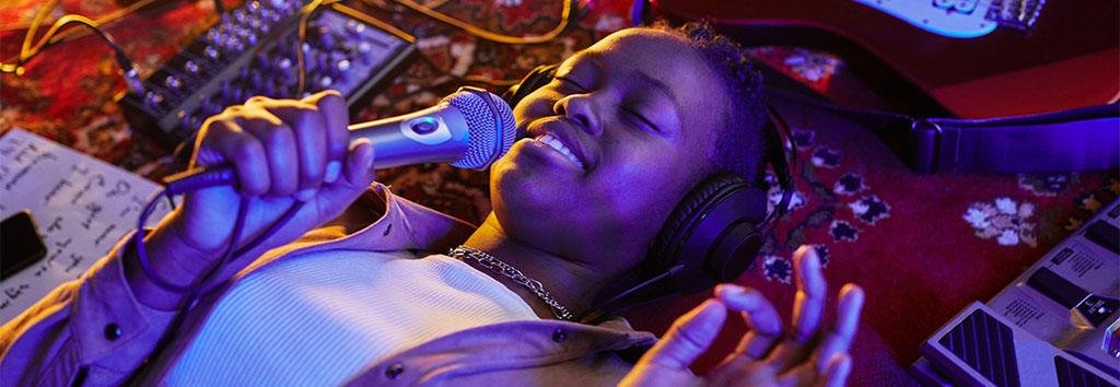 Woman singing into a microphone while reclining with headphones on