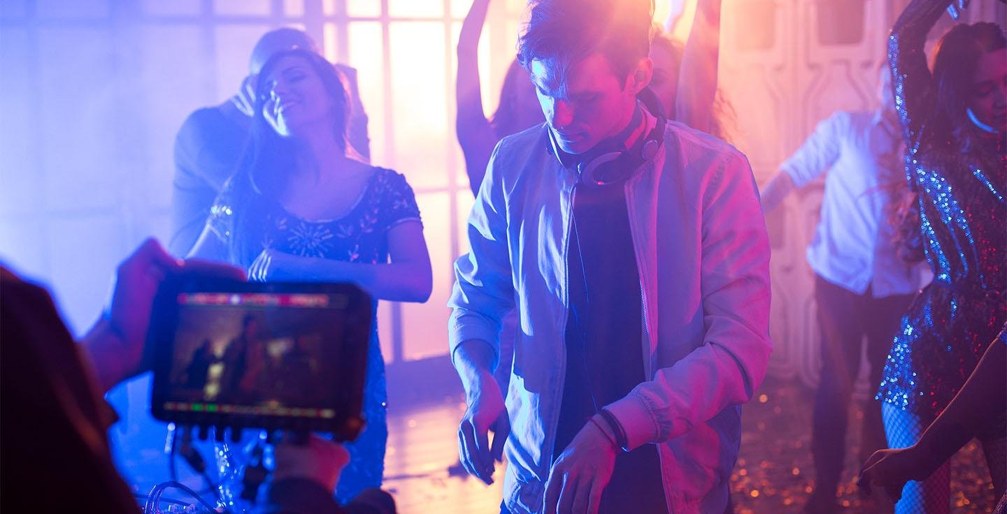 DJ performing under colourful purple and blue lighting at a party