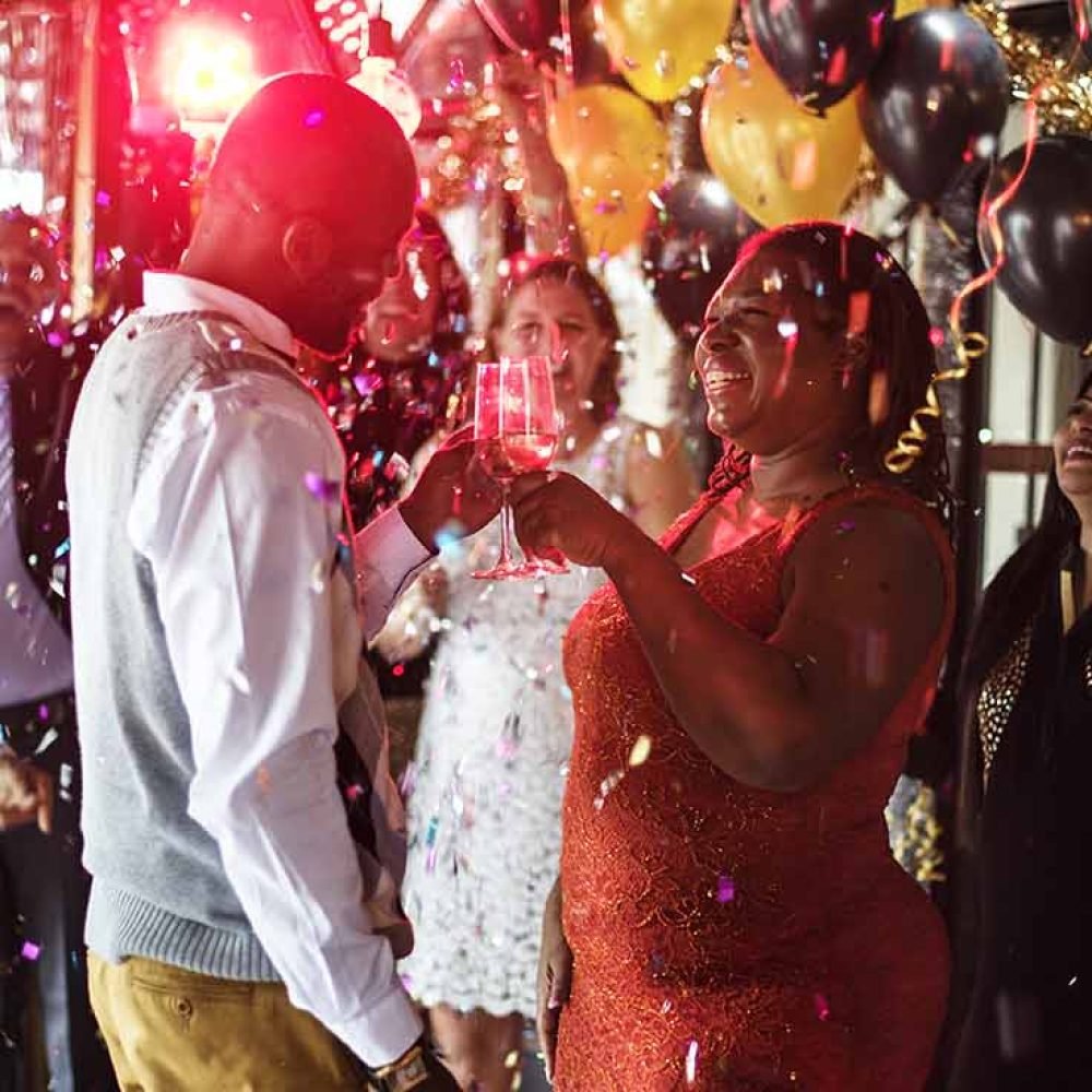 Couple dancing under party lights with confetti and balloons