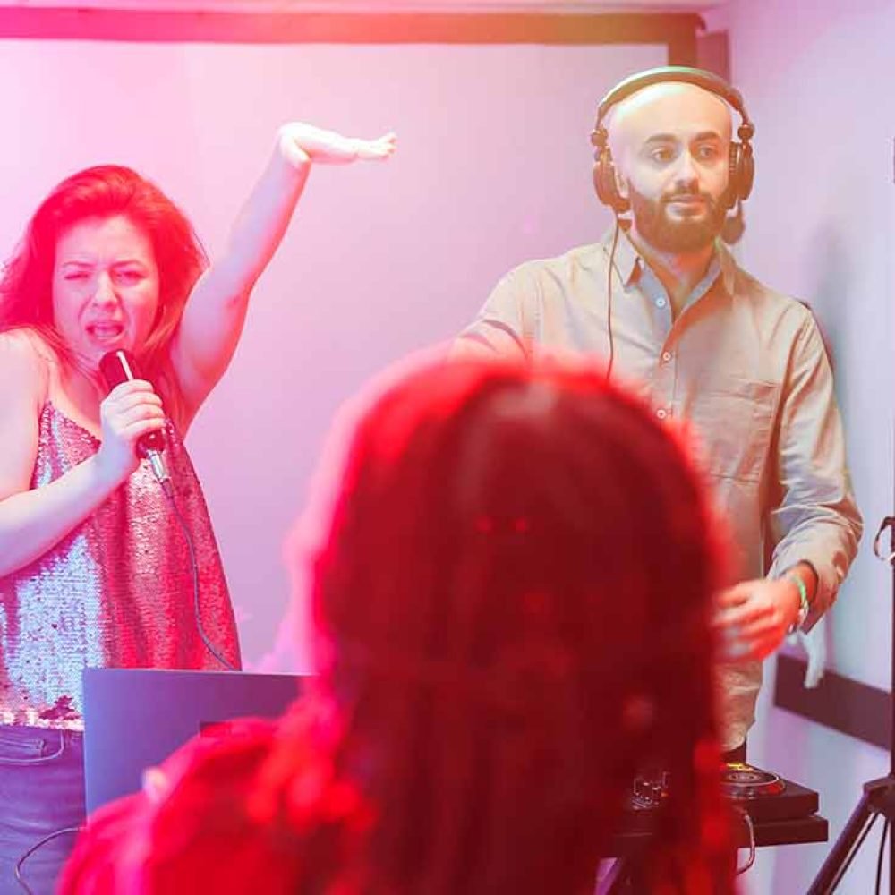 Man singing karaoke with crowd behind him on stage.